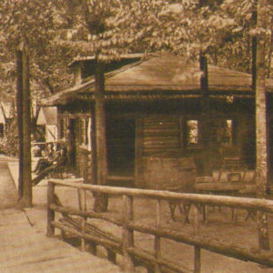 Men Sitting in Front of a Cabin Nestled in the Trees